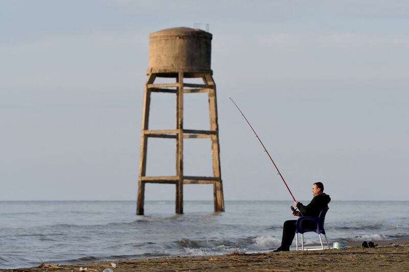 A fishermen holds his line near a submerged water tower on the Adriatic shore in Seman, Albania. The shores of the Balkan country are among the most affected in Europe by erosion, experts say, who blame climate change and urbanisation for the scourge. AFP