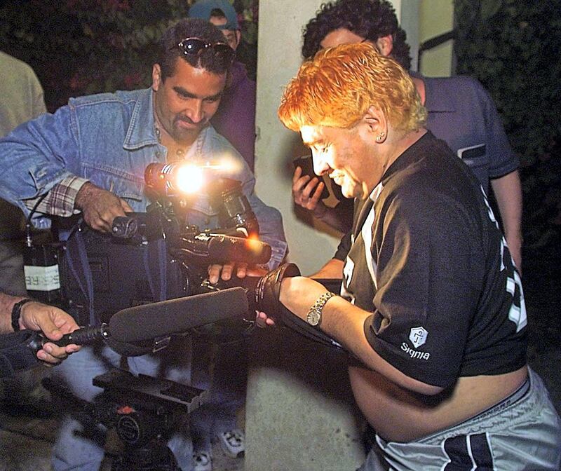 Argentinian football legend Diego Maradona (R) wipes the lens of a television camera during the celebration for his wife's birthday at a hotel in Havana 22 January, 2000.  Maradona is in undergoing a drug rehabilitation therapy at a clinic in Havana from his cocaine habit.   (ELECTRONIC IMAGE)   AFP PHOTO (Photo by ADALBERTO ROQUE / AFP)