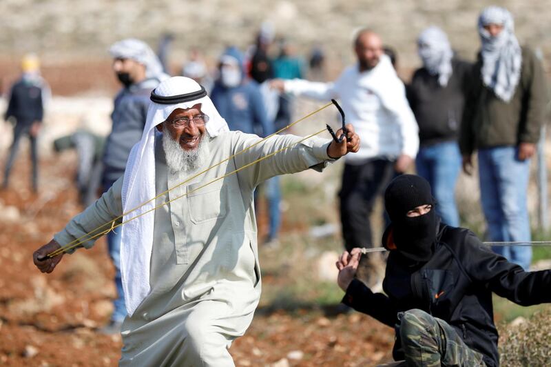 A Palestinian demonstrator uses a slingshot to hurl stones towards Israeli troops during a protest against Israeli settlements, in Deir Jarir in the Israeli-occupied West Bank. Reuters