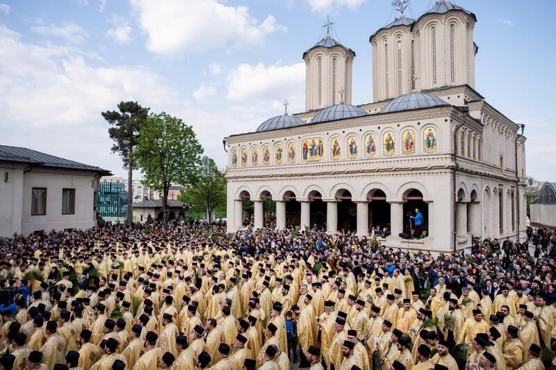 Romanian Orthodox priests and believers stand outside the Patriarchal Cathedral after an Orthodox Palm Sunday pilgrimage in Bucharest. AP