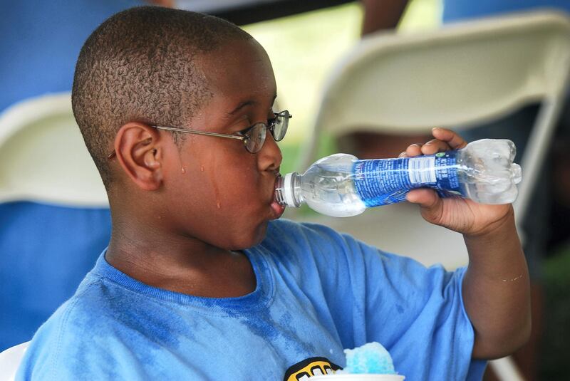 AYCHT9 Child drinking water during a summer heat wave sweating