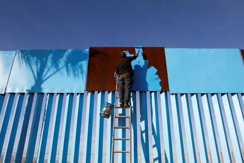 An artist paints a part of a section of the wall separating Mexico and the United States as seen from Playas Tijuana, Mexico. Jorge Duenes / Reuters