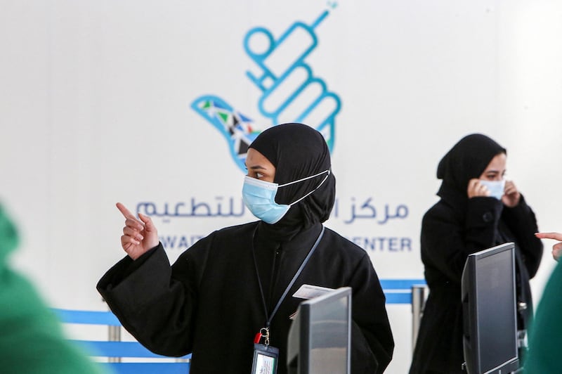 A mask-clad woman gestures as she stands at the reception of a the make-shift COVID-19 coronavirus vaccination centre erected at the Kuwait International Fairground in the Mishref suburb south of Kuwait City on December 29, 2020. (Photo by YASSER AL-ZAYYAT / AFP)