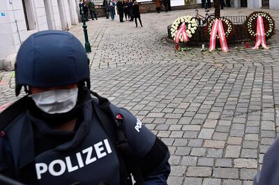 A policeman stands next to wreathes placed in the name of the Austrian Parliament, the President and the Chancellor in order to pay homage to the victims of a shooting in Vienna on November 3, 2020, one day after the shooting at multiple locations across central Vienna. A huge manhunt was under way after gunmen opened fire at multiple locations across central Vienna in the evening of November 2, 2020, killing at least four people in what Austrian Chancellor Sebastian Kurz described as a "repulsive terror attack". / AFP / Joe Klamar
