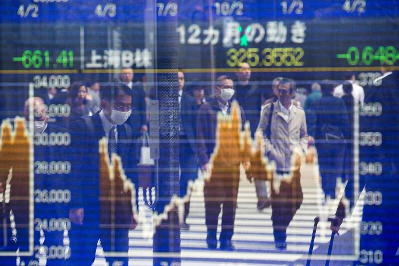 Pedestrians are reflected on a stock indicator in Tokyo, Japan. Behrouz Mheri / AFP Photo