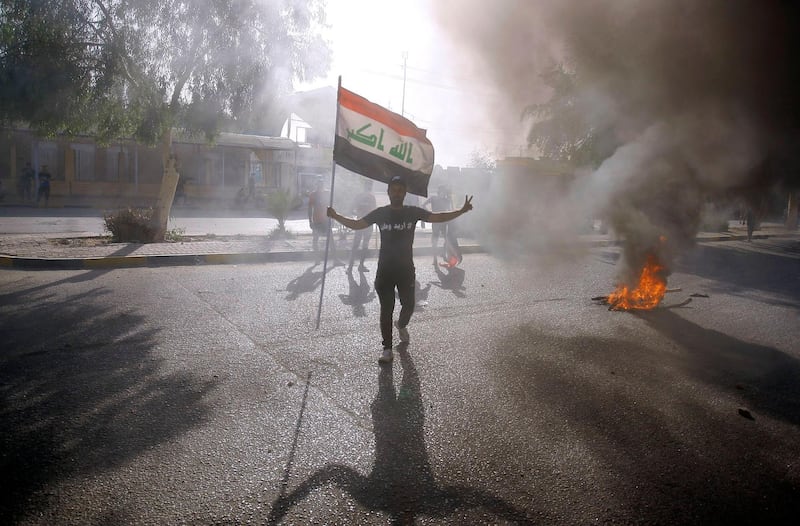 An Iraqi protester holds his national flag during a demonstration in Iraq's central holy shrine city of Najaf on June 8, 2020.  / AFP / STR
