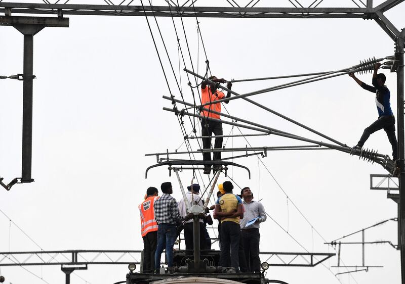 Officials and ground staff inspect an electric train track in New Delhi.  AFP