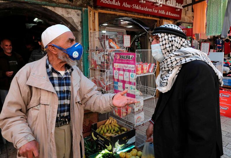 Palestinian men talk in the centre of the occupied West Bank town of Hebron during the coronavirus pandemic. AFP