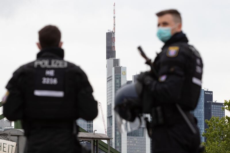 Police officers wearing face masks are pictured in front of Commerzbank and Helaba headquarters during a rally against restrictions in place to limit the spread of the new coronavirus COVID-19 pandemic on May 23, 2020 in Frankfurt am Main, western Germany. / AFP / Yann Schreiber
