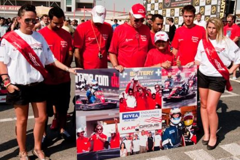 Jean Louis Hissette, centre, and others stand for a minute of silence in memory of his son Christophe before the start of a 24-hour karting event at Dubai Autodrome yesterday.