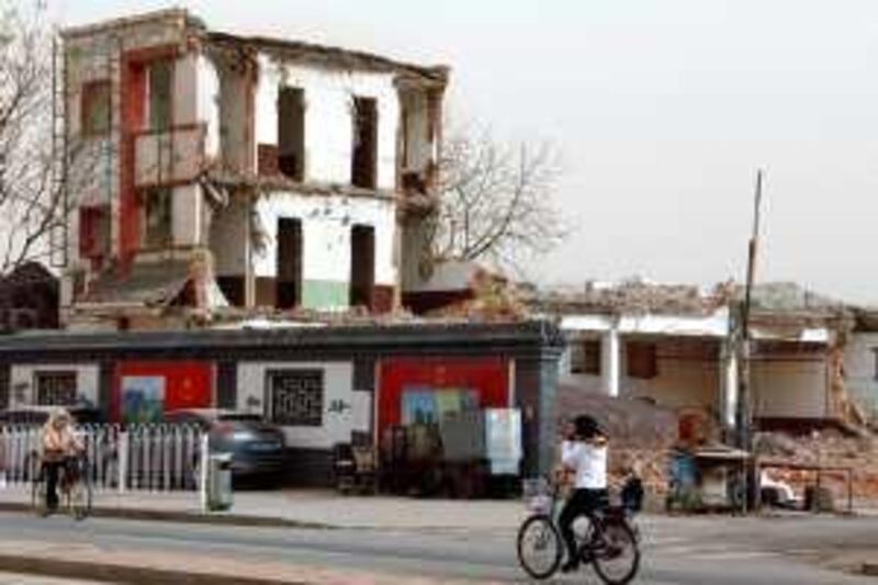 People ride their bicycles past a partially demolished residential block in central Beijing March 23, 2010. As part of a broader government campaign to rein in fast-rising housing and land prices, China has ordered 78 state companies whose core business is not property to submit plans to divest from the sector within 15 working days, state media reported on Tuesday.    REUTERS/David Gray      (CHINA - Tags: EMPLOYMENT BUSINESS) *** Local Caption ***  DBG207_CHINA-PROPER_0323_11.JPG *** Local Caption ***  DBG207_CHINA-PROPER_0323_11.JPG