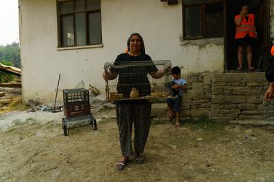 A woman holds up animals ready for transport
