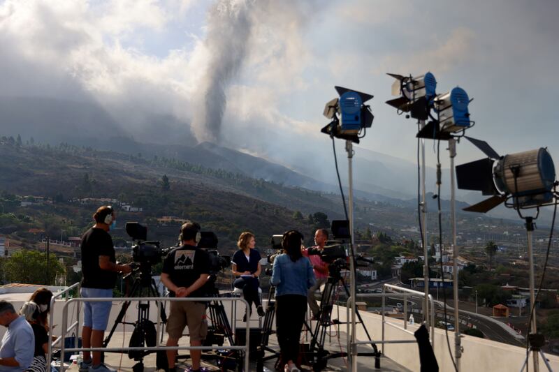 Members of the media work in La Palma as smoke rises following the eruption. Reuters