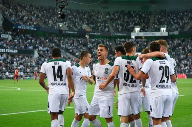 Gladbach's French forward Alassane Plea (C) is congratulated by teammates after scoring his team's first goal.
