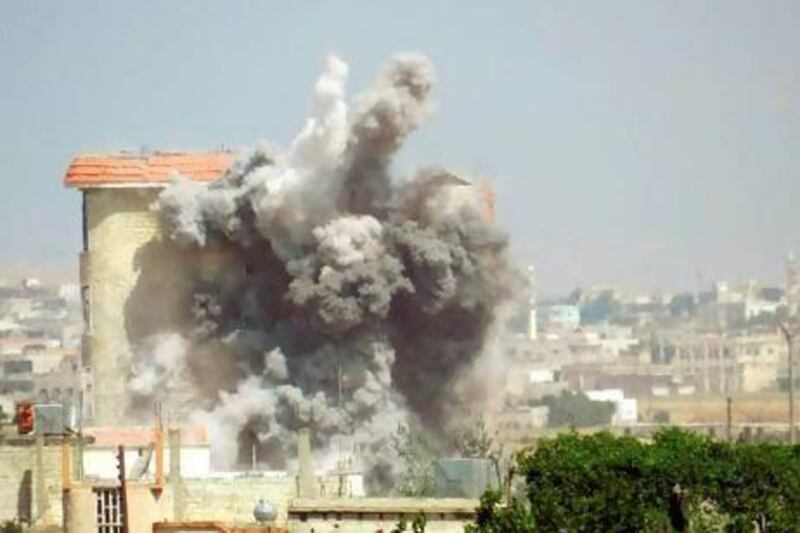 Smoke rises as a mortar shell hits a building in the town of Al Hula in the Syrian province of Homs.