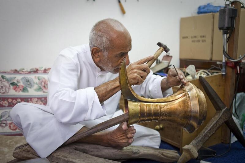 Ismail Ali Al Hassan, 74, delicately hammers patterns on one of his dallahs. The third-generation dallah craftsman is the last man in the UAE to make the traditional coffee pots by hand. Razan Alzayani / The National