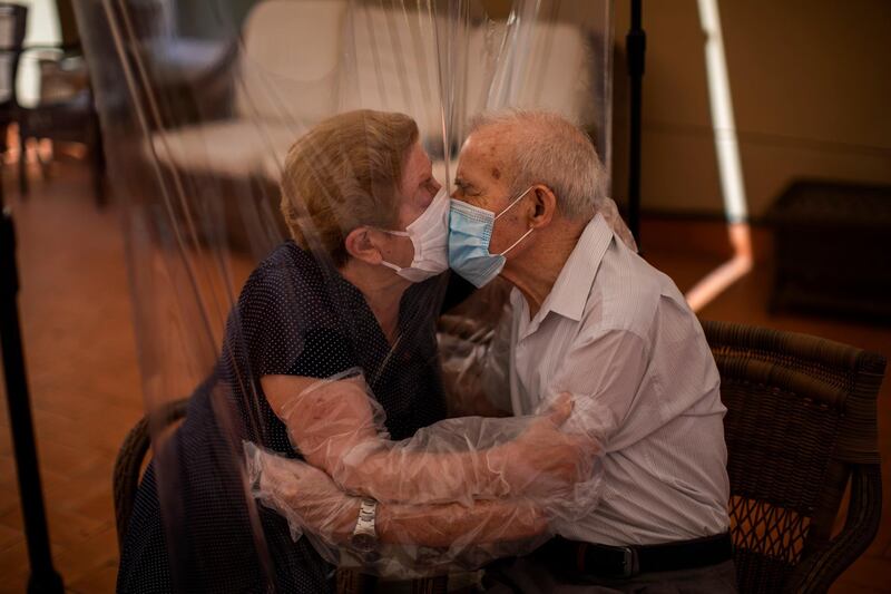 Agustina Cañamero, 81, and Pascual Pérez, 84, hug and kiss through a plastic film screen to avoid contracting the new coronavirus at a nursing home in Barcelona, Spain. AP