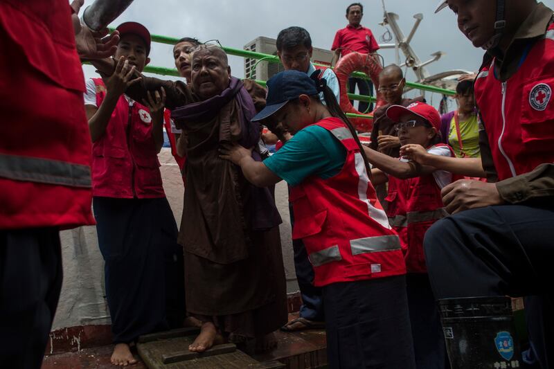 Members of Myanmar's Red Cross help a Buddish nun, who are fleeing a conflict area, as he arrives in Sittwe jetty, in Rakhine State on August 30, 2017.
At least 18,500 Rohingya have fled into Bangladesh in the last six days since renewed fighting broke out between militants and the army in neighbouring Myanmar, the International Organization for Migration said. / AFP PHOTO / YE AUNG THU