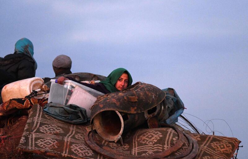 People ride in the back of a truck with furniture, mattresses, and blankets while passing by an internally-displaced persons camp by Dayr Ballut near the Turkish border in the west of Syria's northern province of Aleppo, fleeing advancing Syrian government forces in Idlib and Aleppo provinces. AFP