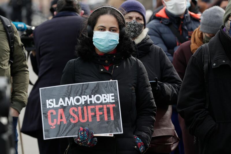 A woman holds a placard reading "enough of islamophobia" as protesters demonstrate against a bill dubbed as "anti-separatism", in Paris on February 14, 2021. French lawmakers a few weeks ago began debating a controversial bill against what the interior minister described as the "disease" of Islamist extremism eating away at the country's unity. President Emmanuel Macron has pushed for the legislation, which would tighten rules on issues ranging from religious-based education to polygamy, since a spate of attacks blamed on extremists late last year. / AFP / GEOFFROY VAN DER HASSELT

