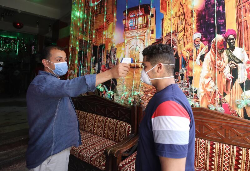 A customer gets his temperature measured by a worker in a cafe in Cairo. EPA
