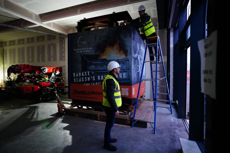 Workers with the crate containing 'Season's Greetings' at a retail unit at Ty'r Orsaf, Port Talbot.