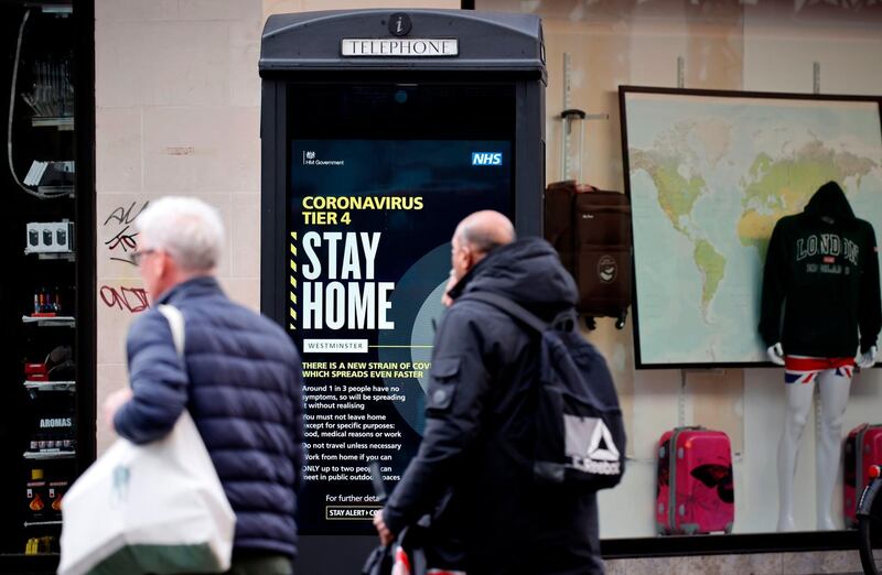 Pedestrians walk past a COVID-19 Tier 4 information sign in central London on December 23, 2020. Britain's public health service urged Prime Minister Boris Johnson on Wednesday to extend the country's Brexit transition period or risk pushing hospitals already struggling with coronavirus "over the edge" in the event of a no-deal departure from the EU single market. / AFP / Tolga Akmen
