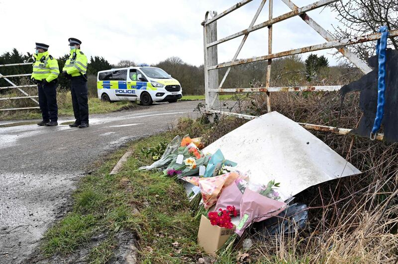 Flowers and messages of condolence for Sarah Everard are seen as police officers patrol near the woodland where police officers found human remains near Ashford, southeast England, on March 12, 2021,  A body found hidden in woodland in Kent has been identified as that of Sarah Everard.
Metropolitan Police Assistant Commissioner Nick Ephgrave announced outside Scotland Yard on March 12, 2021, that the body found hidden in woodland in Kent has been identified as that of Sarah Everard.
 / AFP / Glyn KIRK
