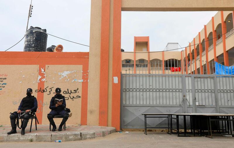 Palestinian police officers loyal to Hamas wearing protective masks, sit outside a school used as a quarantine facility in Deir Al Balah in the central Gaza Strip. AFP