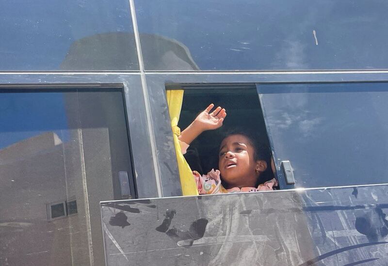 A Sudanese girl with British citizenship waves goodbye to loved ones from a bus before being processed for evacuation. Reuters