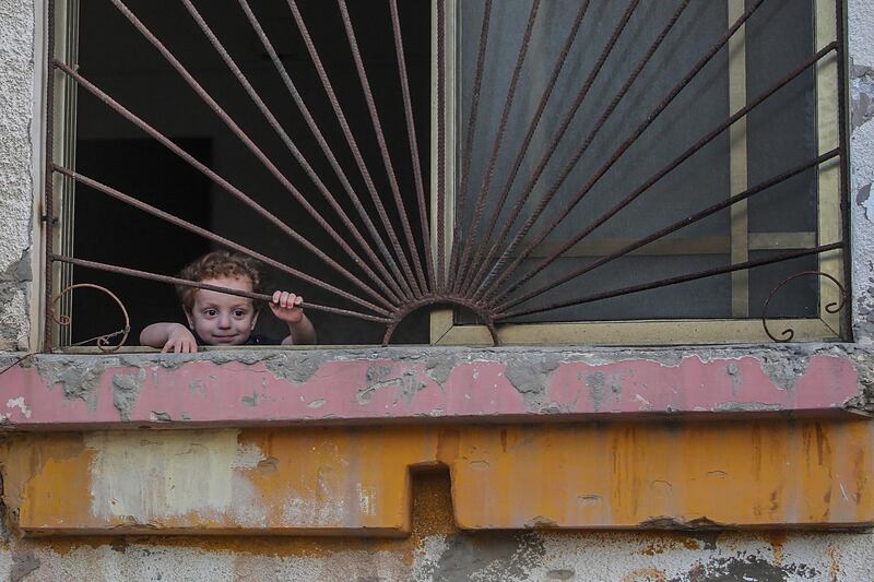 A Palestinian refugee child looks from the window of his family house in the refugee camp of Rafah in the southern Gaza Strip.  EPA