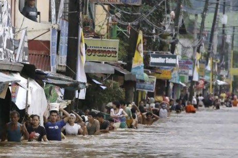 Residents cross a flooded road in Marikina City, east of Manila. The flooding has killed at least 23 people, battered a million others and paralysed the Philippine capital.