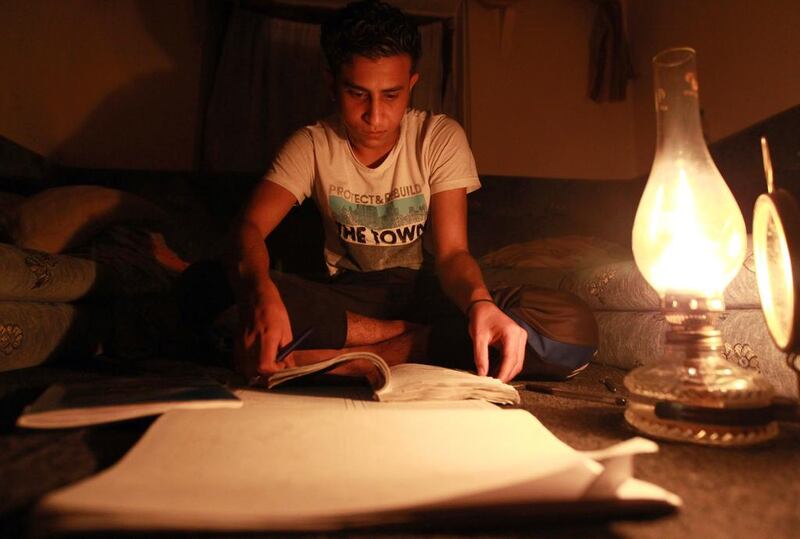 A Yemeni youth reviews his studies on the light of an oil lamp in Sanaa. Yemen suffered a total blackout after gunmen in the eastern province of Marib sabotaged key power lines in the third attack of its kind this month. Mohammed Huwais / AFP