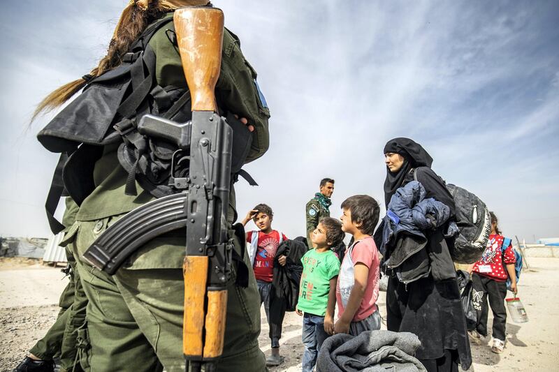 A Kurdish fighter looks on as Syrian women and children, suspected of being related to Islamic State (IS) group fighters, gather at the Kurdish-run al-Hol camp, before being released to return to their homes, in the al-Hasakeh governorate in northeastern Syria, on October 28, 2020. (Photo by Delil SOULEIMAN / AFP)
