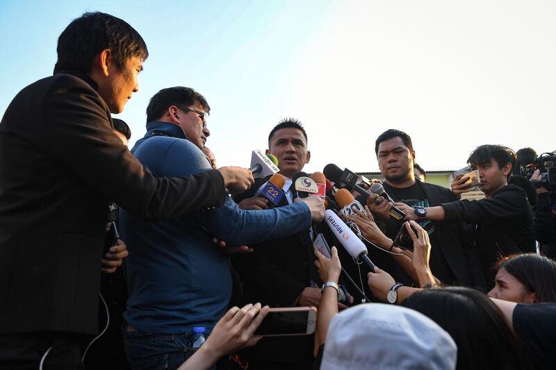Police Lieutenant Kiatisuk "Zico" Senamuang, centre, a Thai football manager speaks to journalists outside the temple. AFP