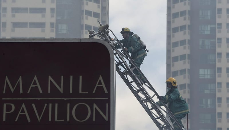 Firemen climb a truck ladder as they battle a fire that hit the Waterfront Manila Pavilion building, a hotel and casino complex in Manila on March 18, 2018. Ted Aljibe / AFP