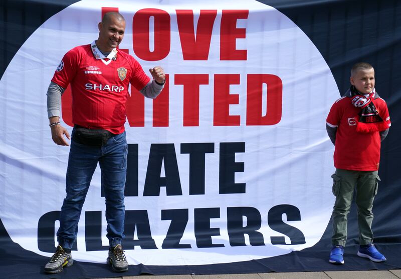 Manchester United fans pose in front of a Love United Hate Glazers banner. PA