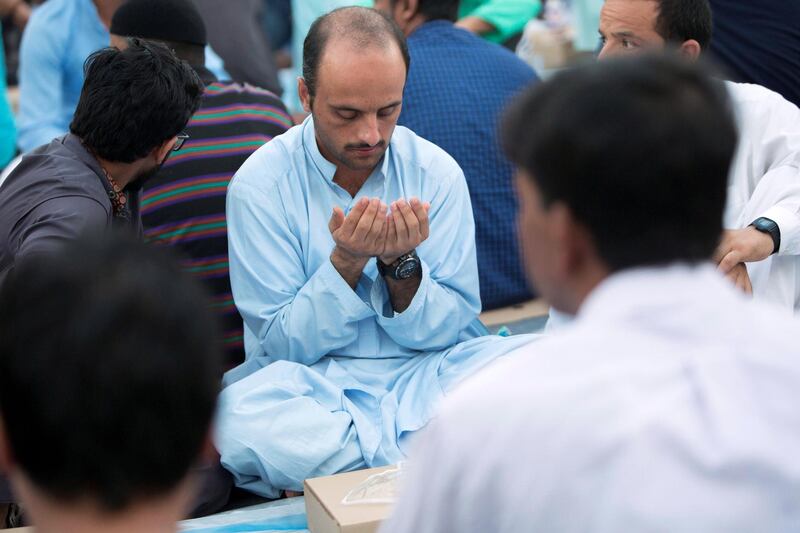 DUBAI, UNITED ARAB EMIRATES -  Some workers starting to pray before breaking their fast. Dubai Police join hands with Berkeley Assets to serve up Iftar dinner to mark Laylatul Qadr for 10,000 labourers with seating for 5,000 and another 5,000 laborers will go home with meal boxes in Al Muhaisnah, Dubai.  Ruel Pableo for The National