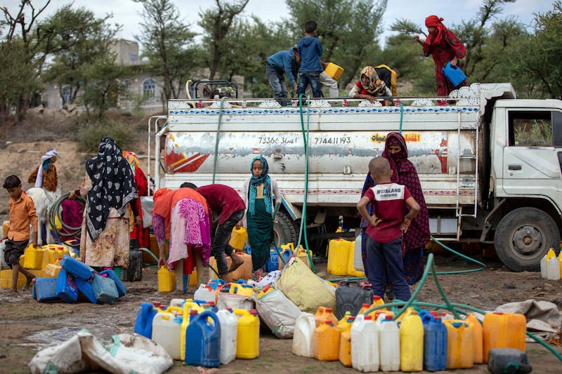 Yemeni women and children collect water from a tanker in Al Maafer district in August. AFP