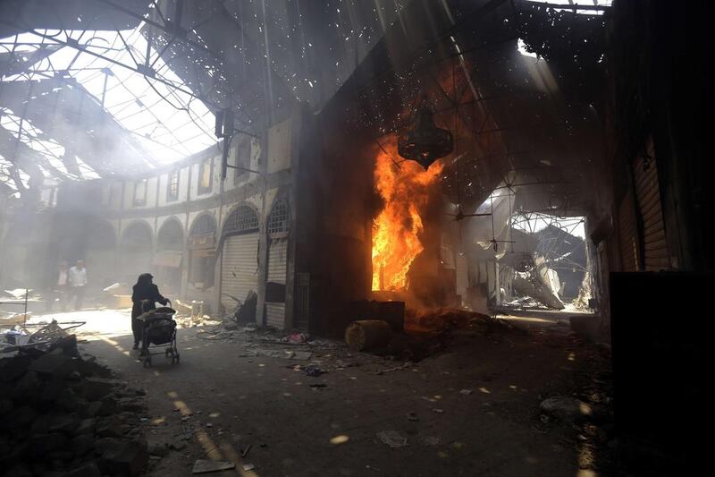 A woman walks past a burning shop in the Maskuf market in the Old City of Homs, some 162 kilometres north of the capital Damascus. Joseph Eid / AFP 