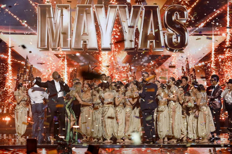 This image released by NBC shows host Terry Crews, left in suit, with members of the female Lebanese dance troupe Mayyas after winning "America's Got Talent," Wednesday, Sept.  14, 2022.  (Trae Patton / NBC via AP)