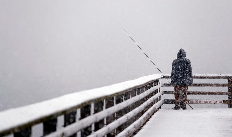 Hershel Odle looks out toward the cityscape lost in a whiteout as he fishes from a pier during a snowstorm in Seattle. AP