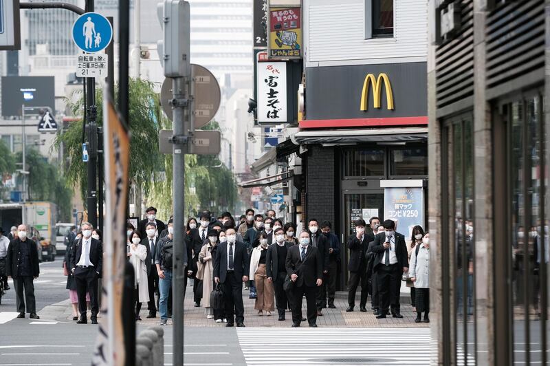 Pedestrians wearing protective masks wait to cross a road in Shinbashi in Tokyo, Japan. Bloomberg