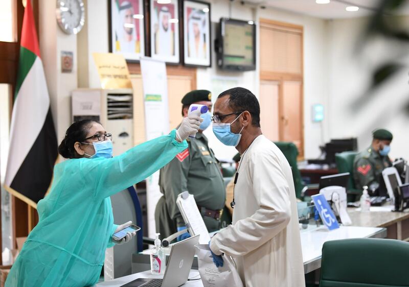 A man wearing a surgical mask has his body temperature reading taken upon arriving at the police station of Naif locality, as part of screenings for COVID-19 coronavirus disease, in the Gulf emirate of Dubai on April 15, 2020.  / AFP / KARIM SAHIB
