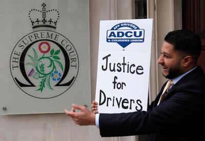 Uber driver and president of the (ADCU), App Drivers & Couriers Union, Yaseen Islam poses with a poster outside the Supreme Court in London, Friday, Feb. 19, 2021. The U.K. Supreme Court ruled Friday that Uber drivers should be classed as â€œworkersâ€ and not self employed.(AP Photo/Frank Augstein)