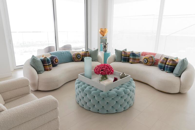 A turquoise tufted velvet coffee table adds a pop of colour in a sitting room dominated by sofas and armchairs upholstered in a warm white boucle. Antonie Robertson / The National