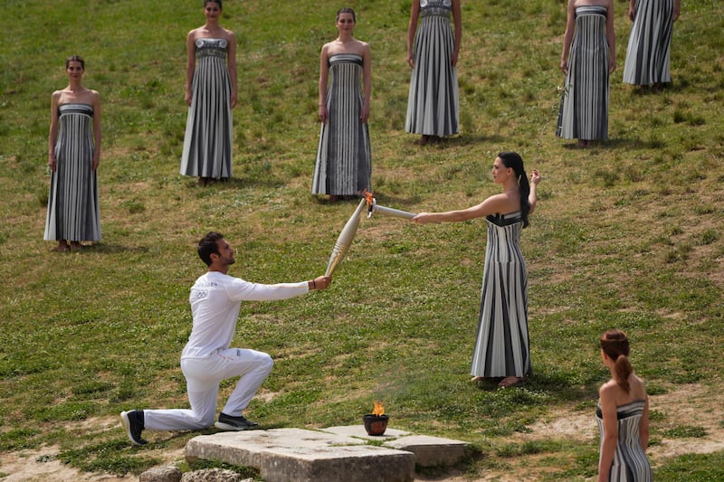 Mina gives the flame to the first torch bearer, Greek olympic gold medalist Stefanos Ntouskos. AP