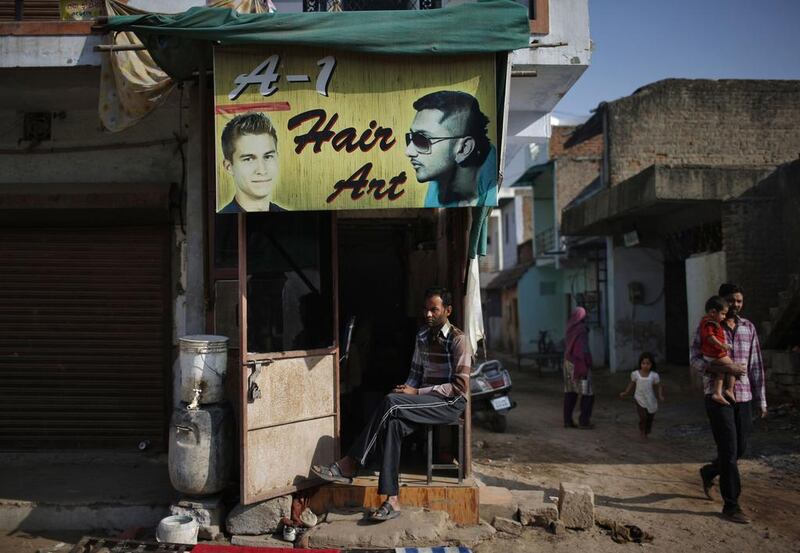 A Muslim man sits outside a hair dressing shop.