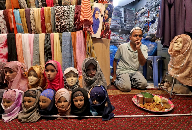 A Muslim shopkeeper selling hijabs waits to have his iftar meal during the holy month in a street market in Mumbai. Reuters