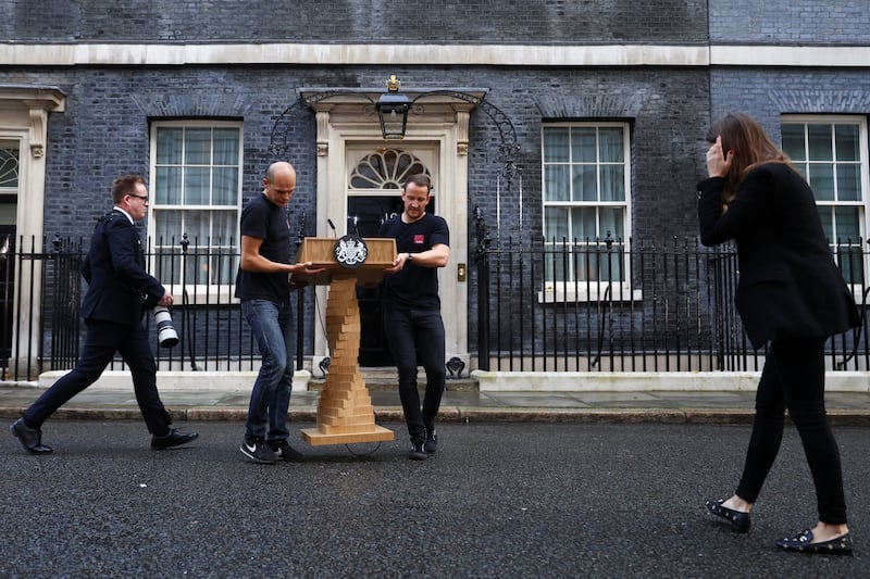Staff place a podium in front of Number 10 Downing Street before Ms Truss delivers a speech. Reuters
